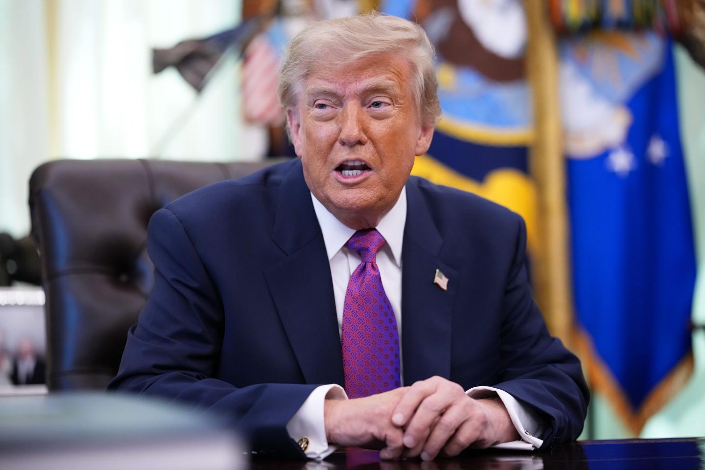 Donald Trump sits at his desk in the Oval Office.