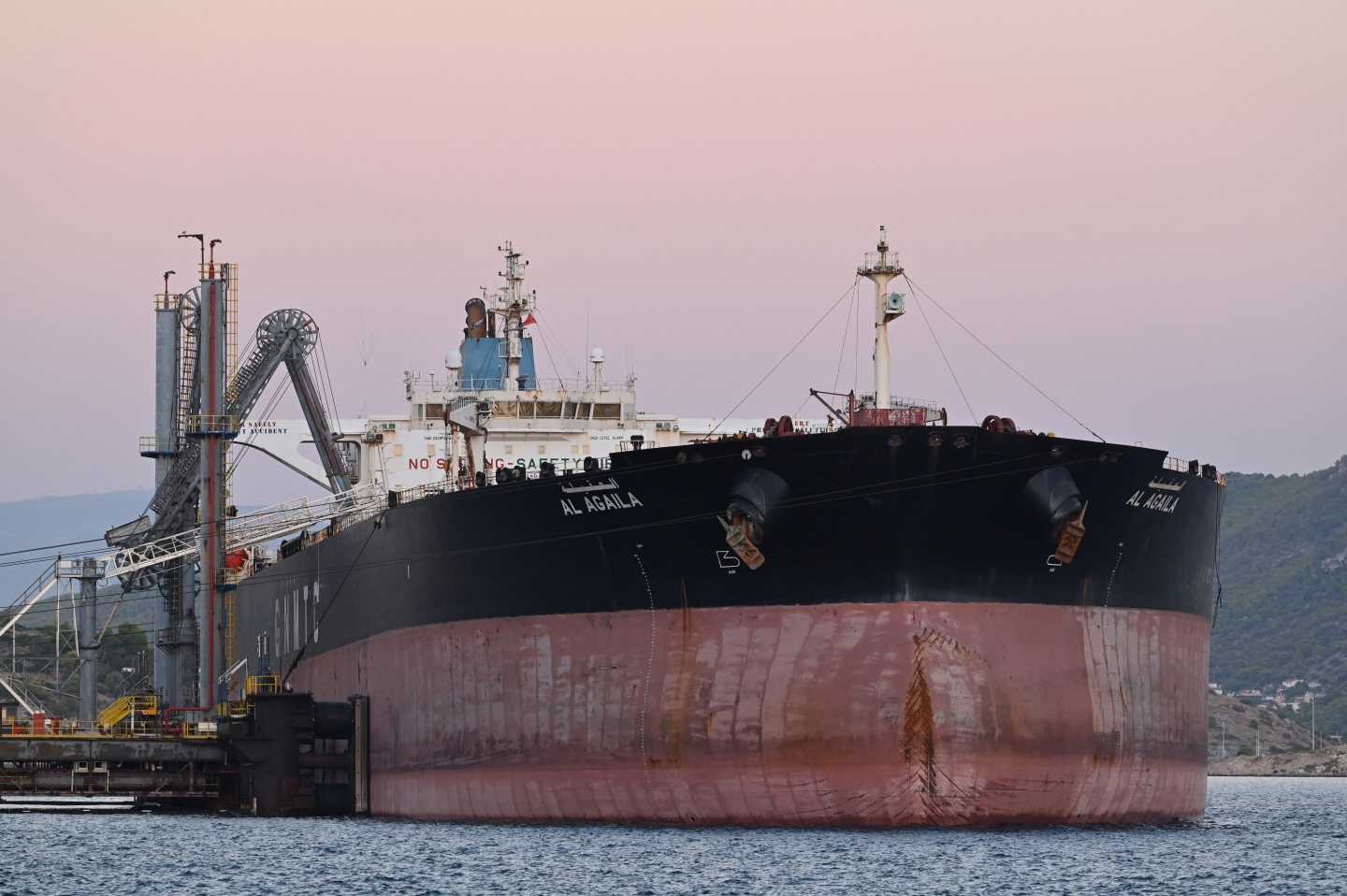 An oil tanker on the water in front of a setting sun.