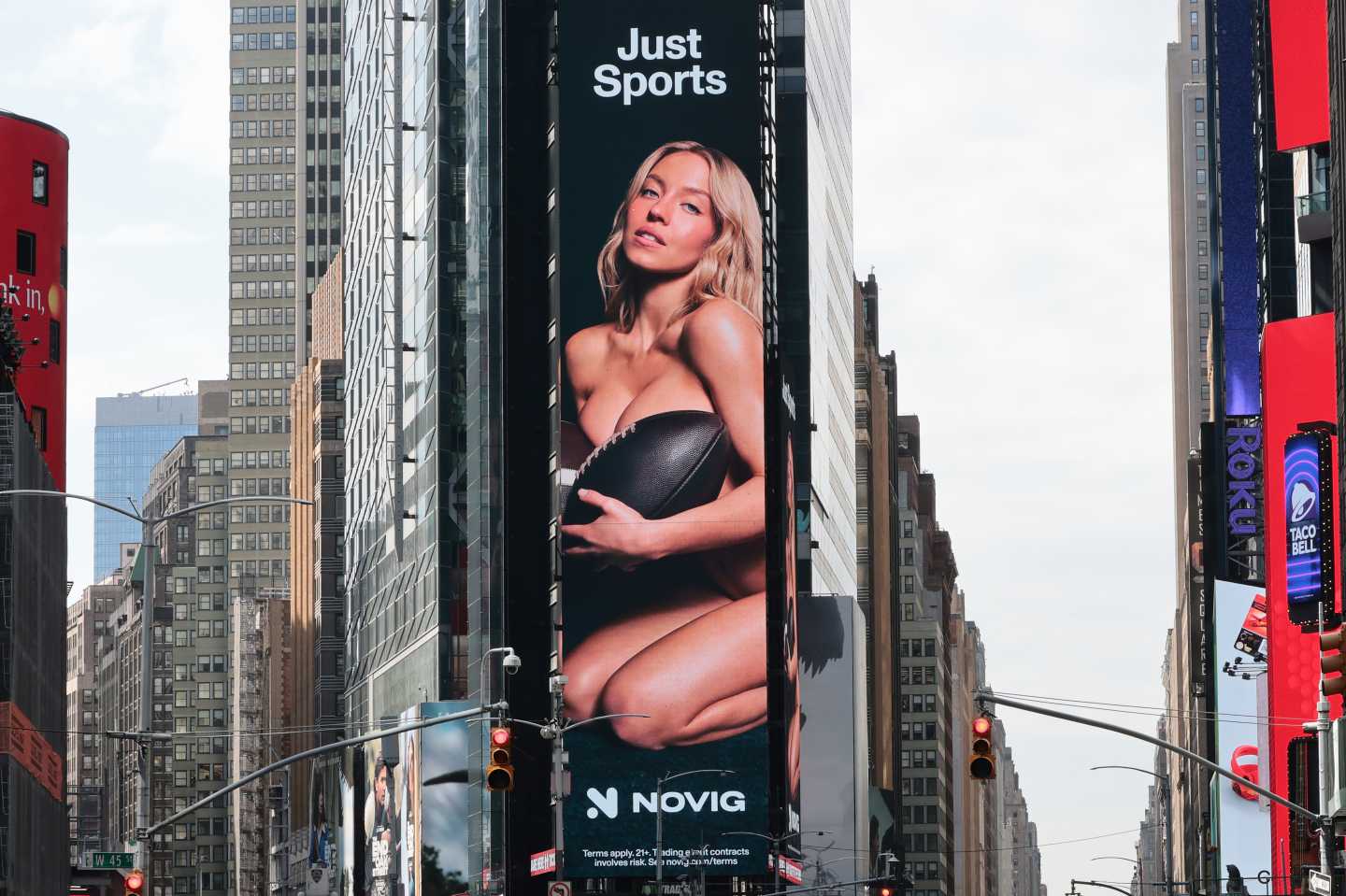 Billboard image of Sydney Sweeney Novig ad where she poses naked with a football covering her chest.