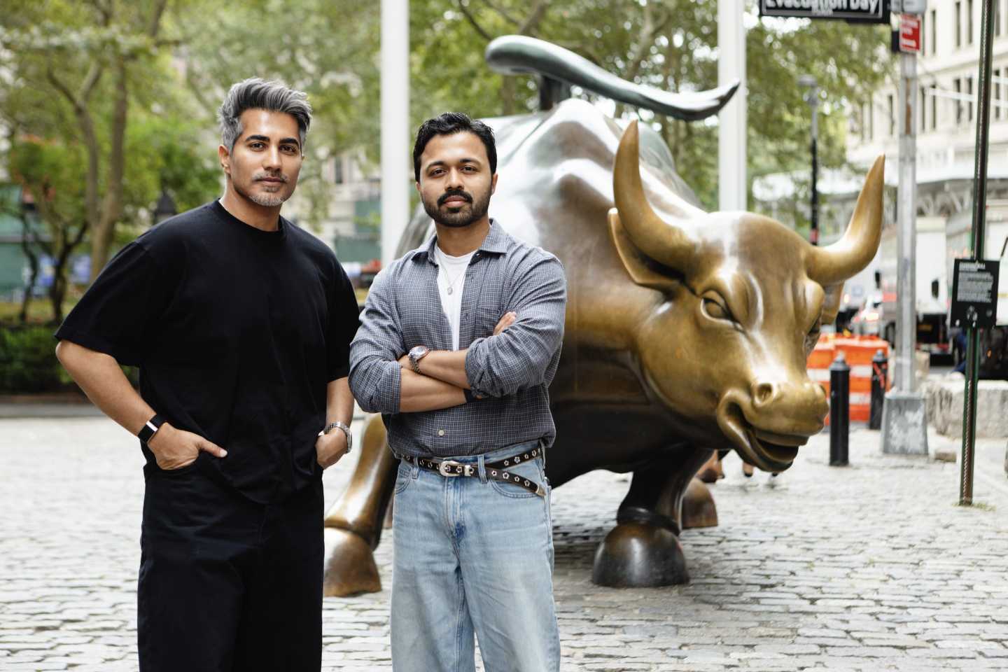 Mustafa Dar (left) and Nabeel Alamgir (right) stand in front of the Charing Bull, the bronze sculpture located in Wall Street.