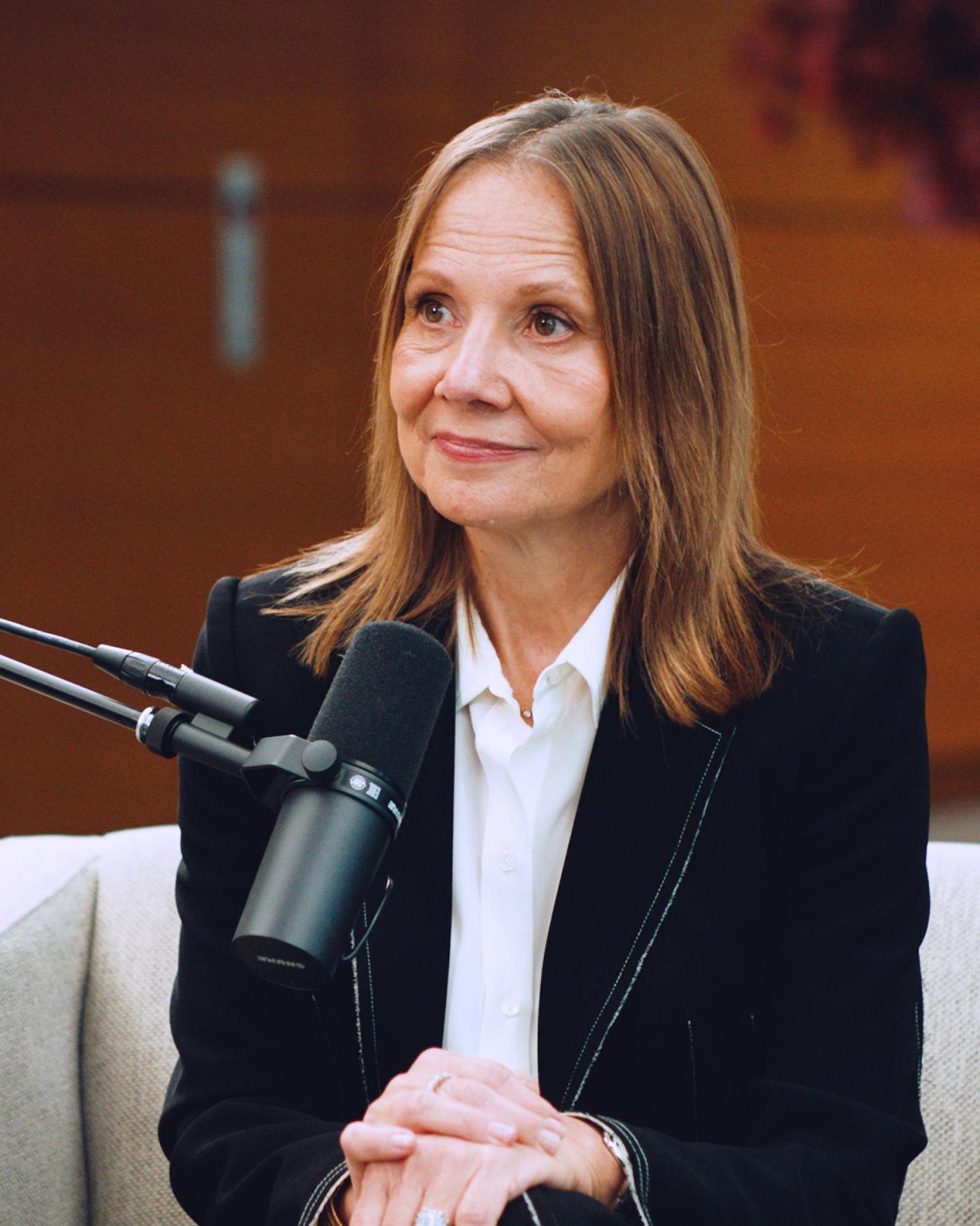 A woman sits in front of a microphone.
