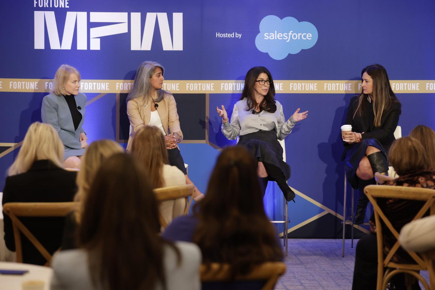 Four women sitting on stools