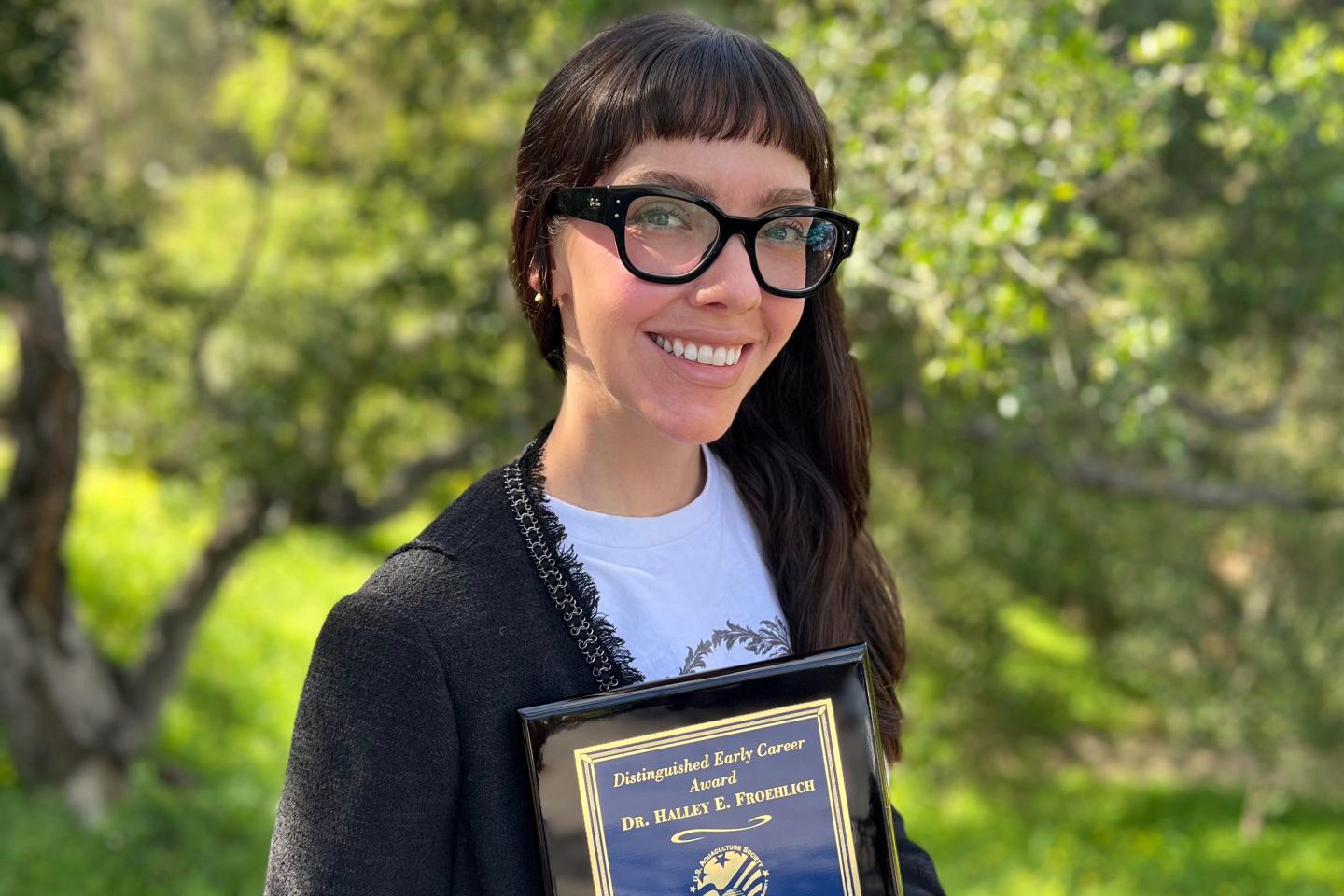 This photo taken with a smart phone and provided by Halley Froehlich shows Froehlich holding a U.S. Aquaculture Society award in Santa Barbara, Calif.