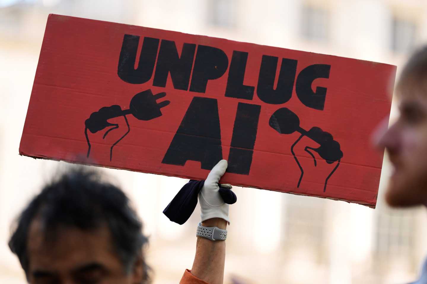 A small group of people supporting restrictions on artificial intelligence hold up signs in front of City Hall before a New York City Council hearing on artificial intelligence safety in New York.