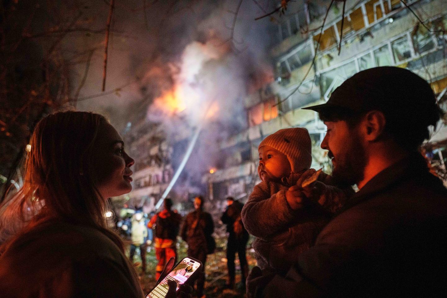 Victoria Deineko, her husband Ievhen Deineko and their daughter Mia look at a multi-story residential building damaged in a Russian missile strike in Kyiv, Ukraine.