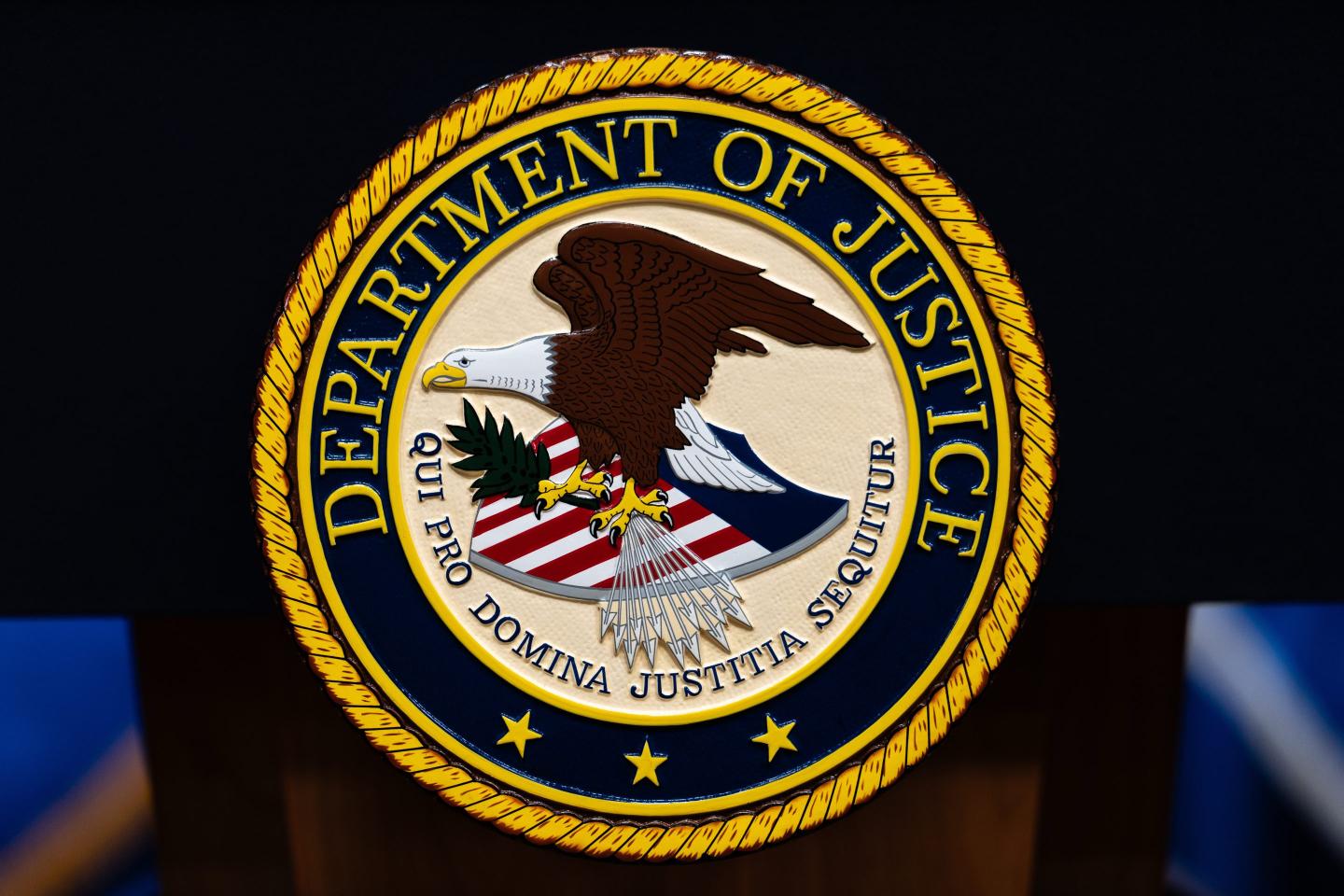 The U.S. Department of Justice logo is seen on a podium before a news conference.