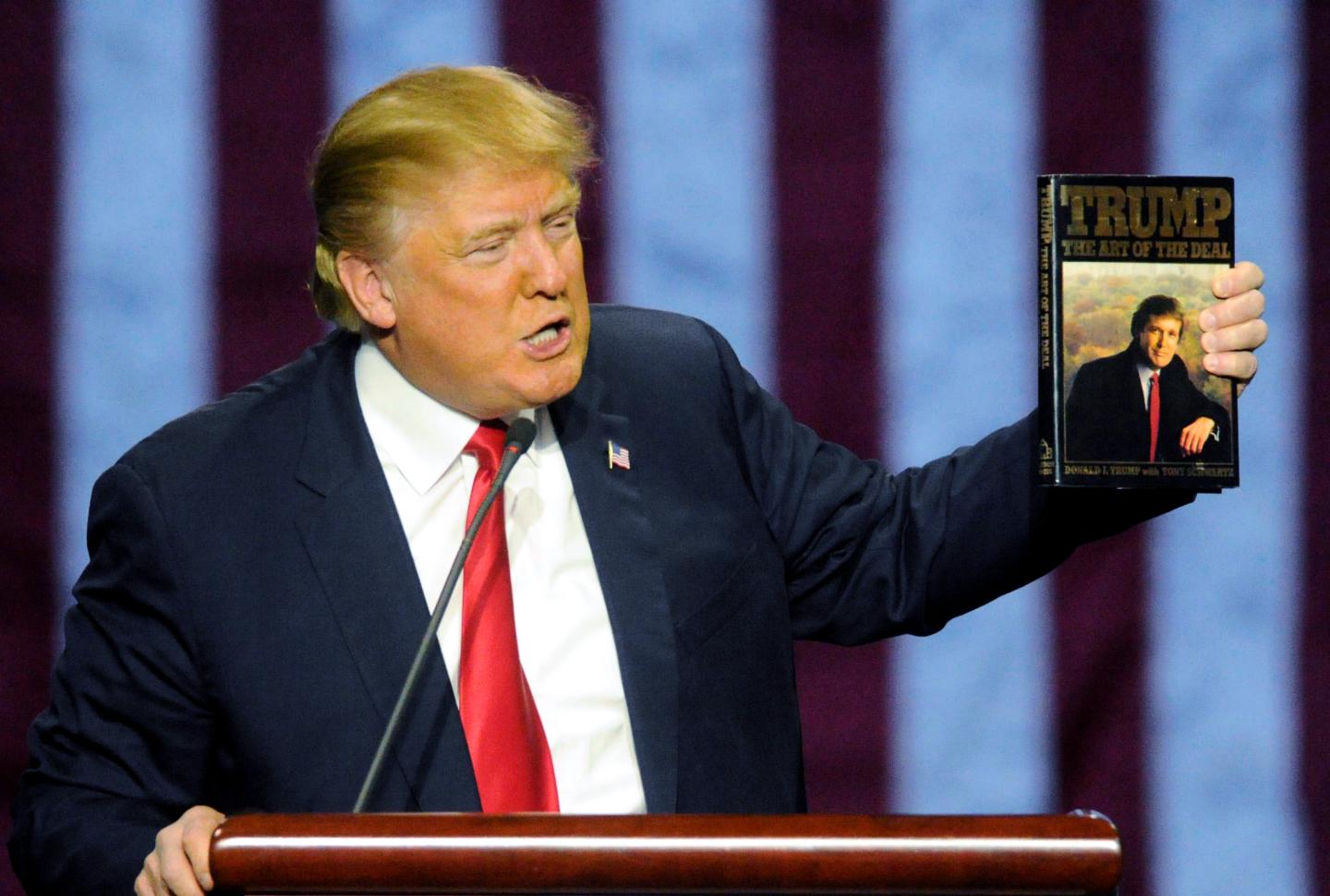 Then-Republican presidential candidate Donald Trump holds up his book "The Art of the Deal," given to him by a fan as he speaks during a campaign stop, Nov. 21, 2015, in Birmingham, Ala.