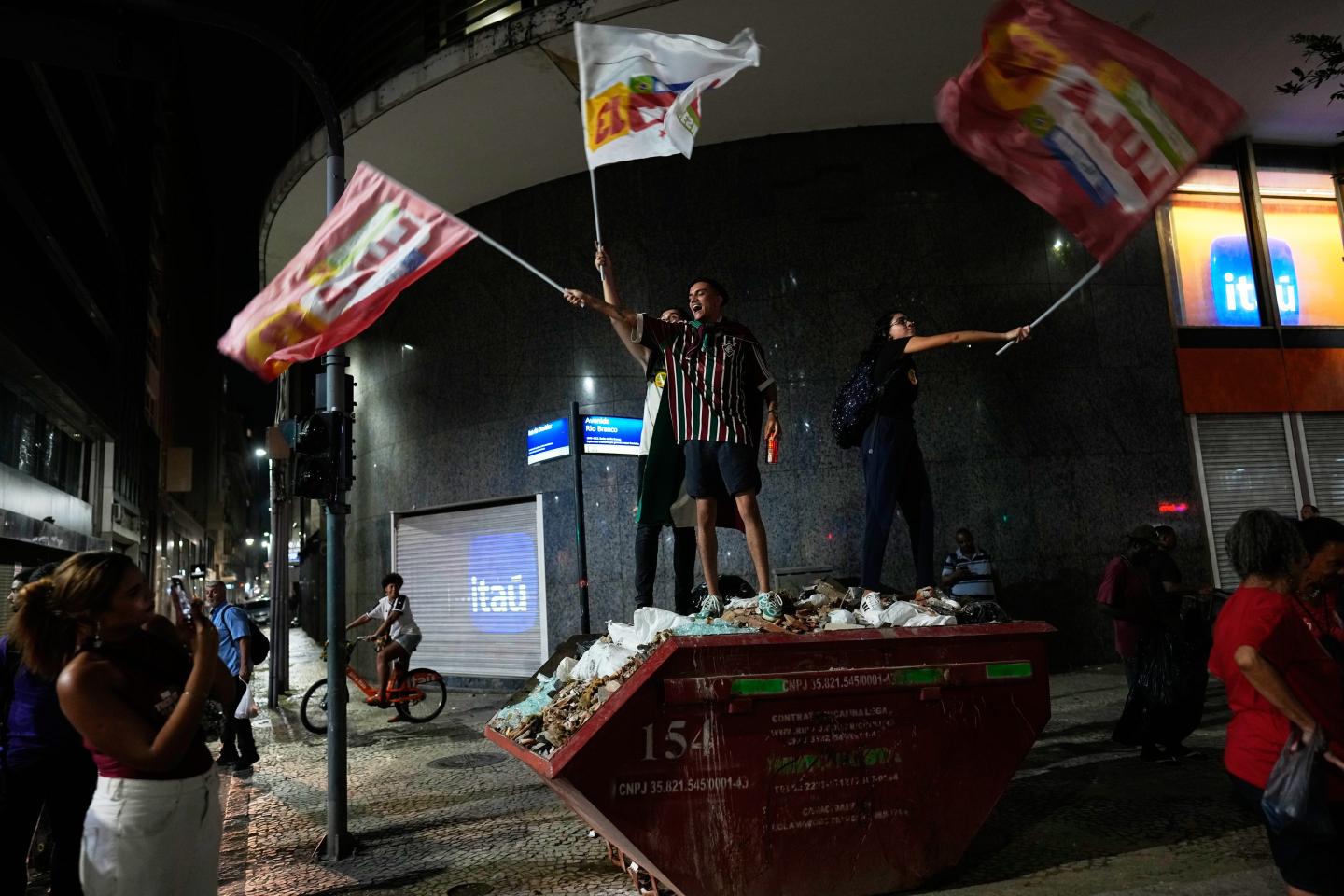 Supporters of Brazilian President Luiz Inacio Lula da Silva, who is running for reelection, stand on a dumpster during a rally ahead of the presidential runoff election, in Rio de Janeiro.