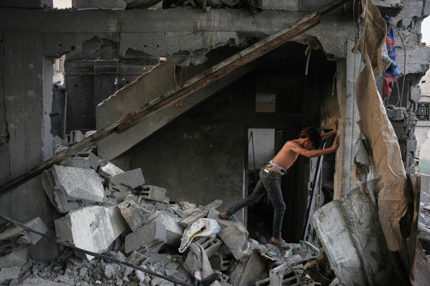 A Palestinian boy makes his way through the rubble of a home destroyed in an overnight Israeli strike in Nuseirat, in the central Gaza Strip.