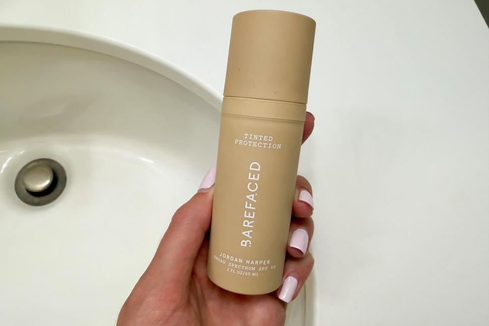 Closeup of a hand holding a bottle of Barefaced Tinted Protection SPF 50+