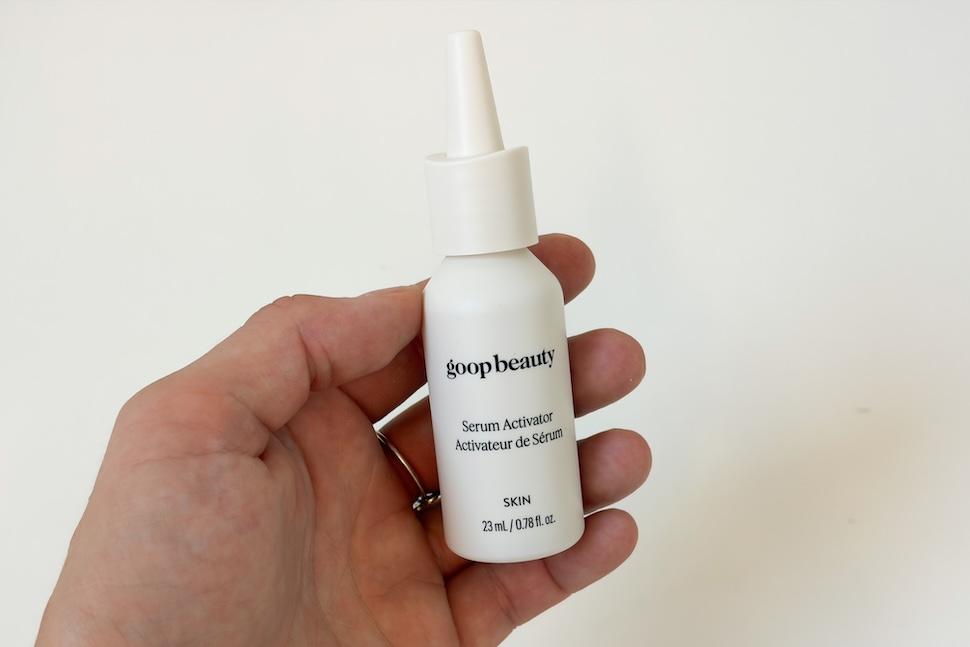 Closeup of a hand holding the dropper bottle for Goop Beauty Vitamin C + Advanced Brightening Serum