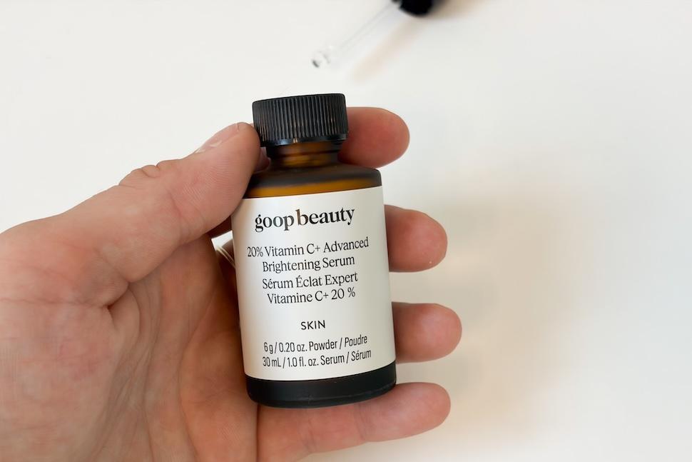 Closeup of a hand holding a bottle of Goop Beauty Vitamin C + Advanced Brightening Serum