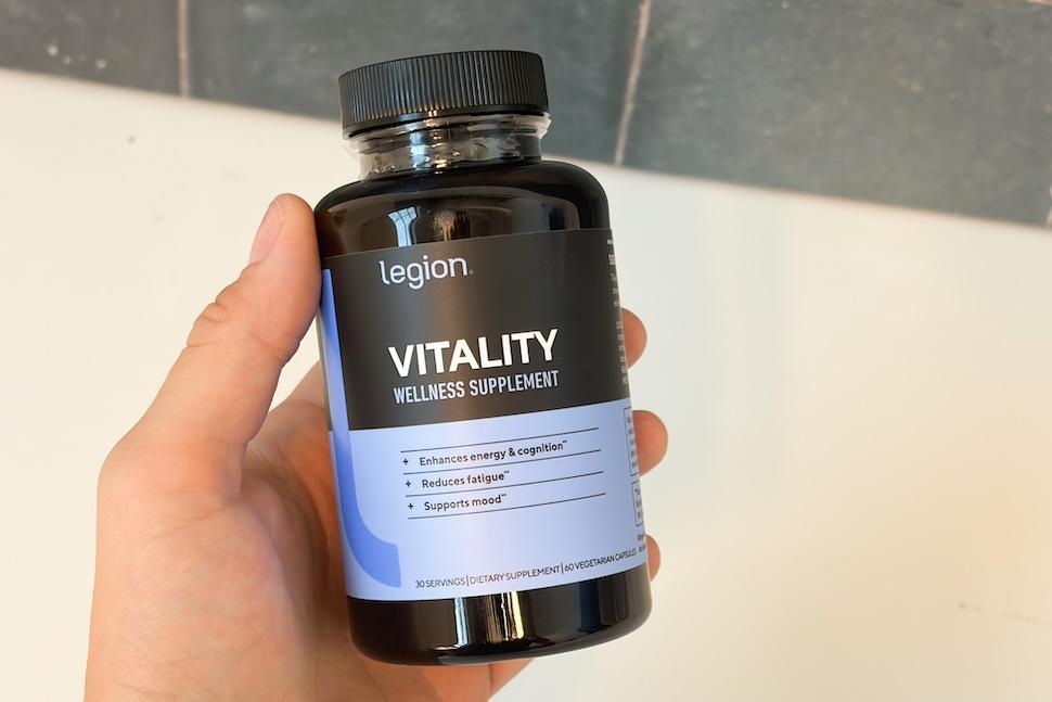 Closeup of a hand holding a bottle of Legion Vitality