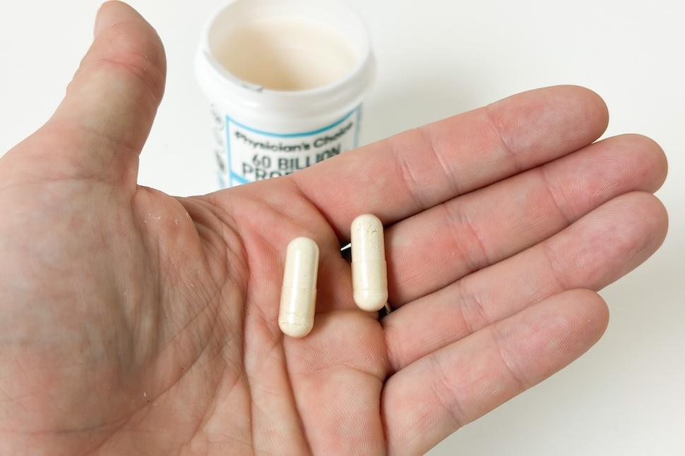 Closeup of an open palm holding two off-white capsules of Physician's Choice 60 Billion Probiotic