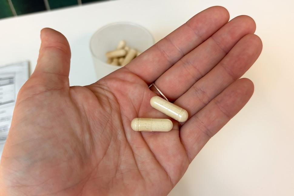 Closeup of an open palm holding two off-white Thesis Clarity capsules