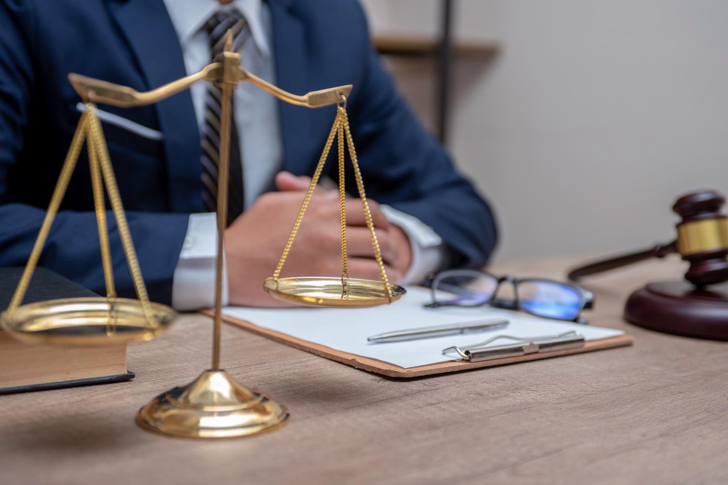 A lawyer working with contract papers and wooden gavel on table in courtroom.