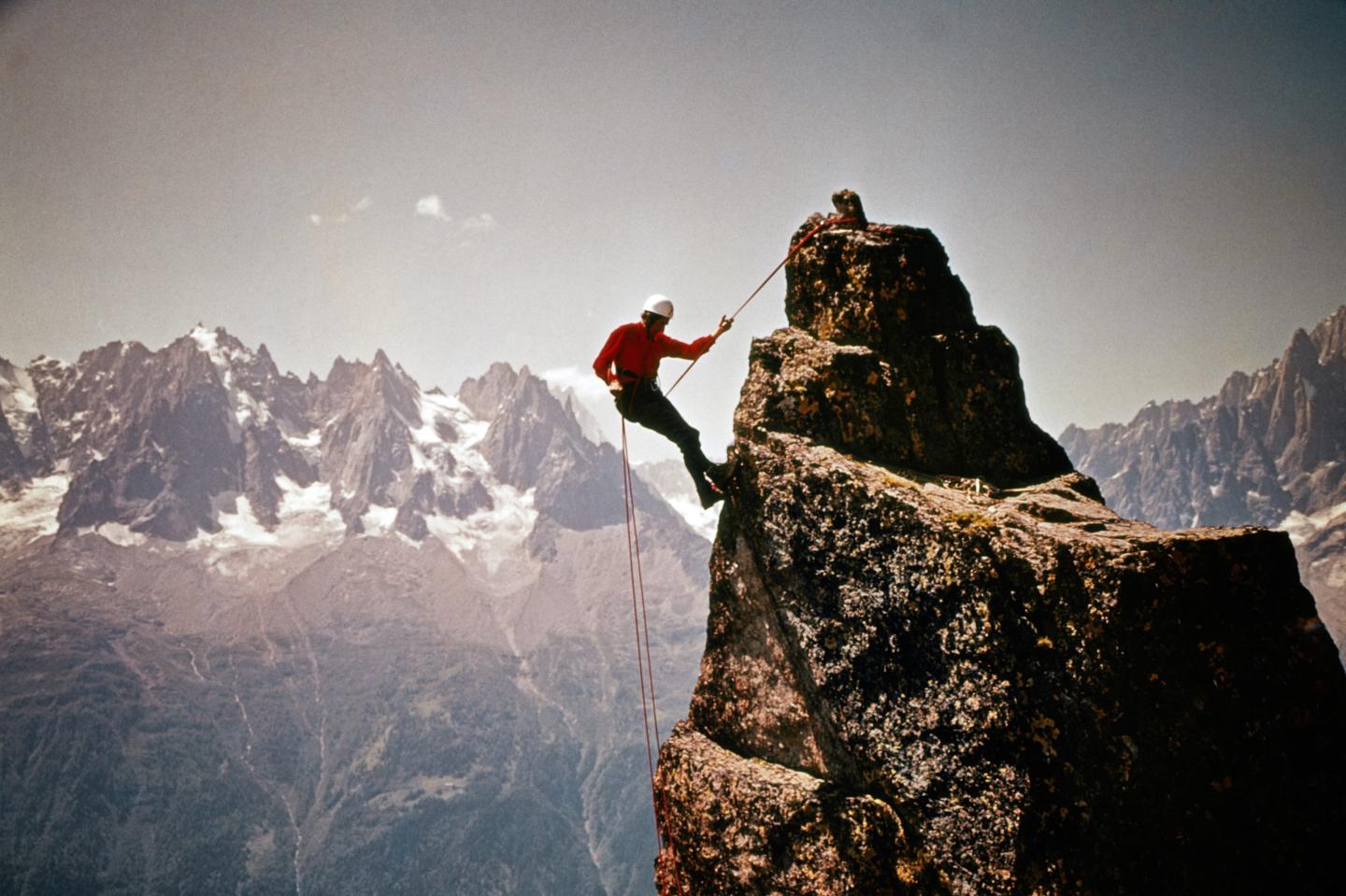 Photo: A climber reaches the top of a mountain peak.