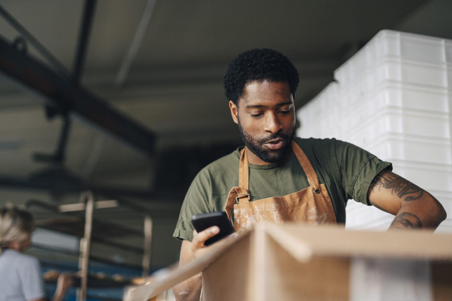 A person on their phone unpacking a box.
