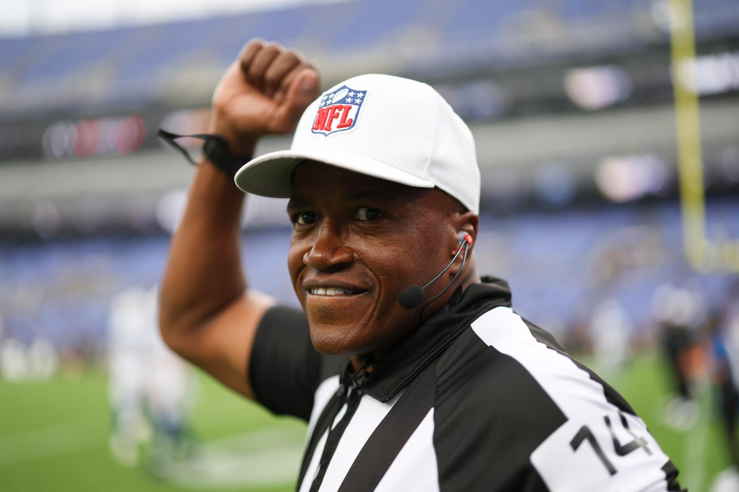 Wearing a white cap with the NFL logo, referee Shawn Smith holds up his fist