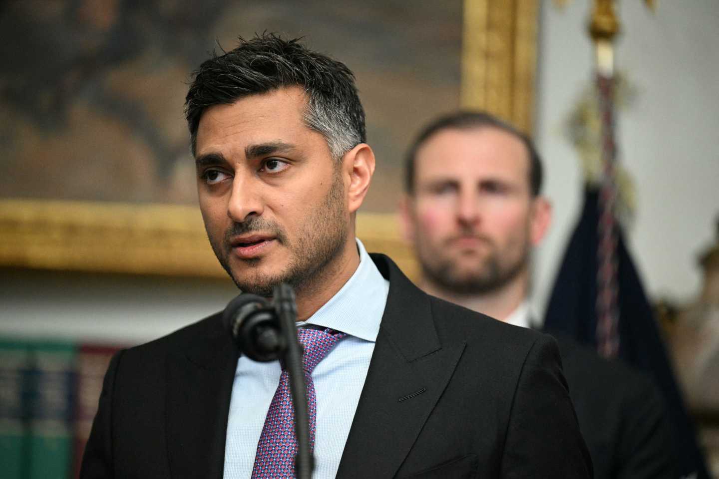 Payward Co-CEO Arjun Sethi wears a suit as he speaks through a microphone