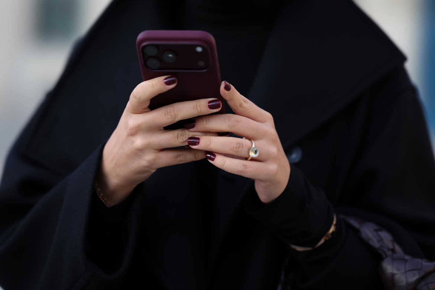 A woman holds a burgundy Apple iPhone 18 Pro during Paris Fashion Week on October 2, 2026. (Photo: Moritz Scholz/Getty Images)