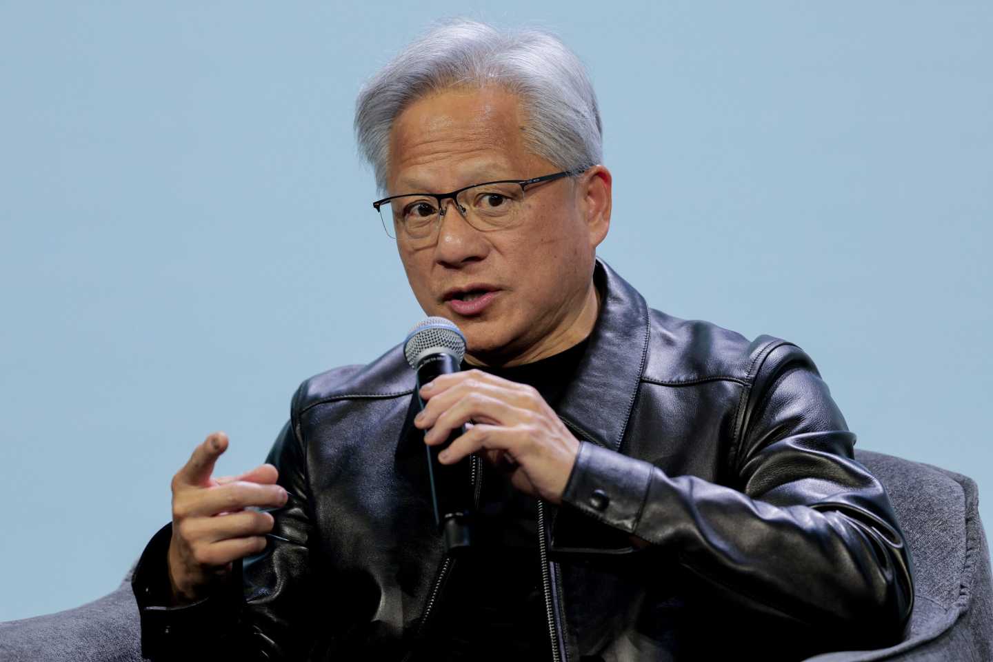 Jensen Huang speaks, holding a microphone