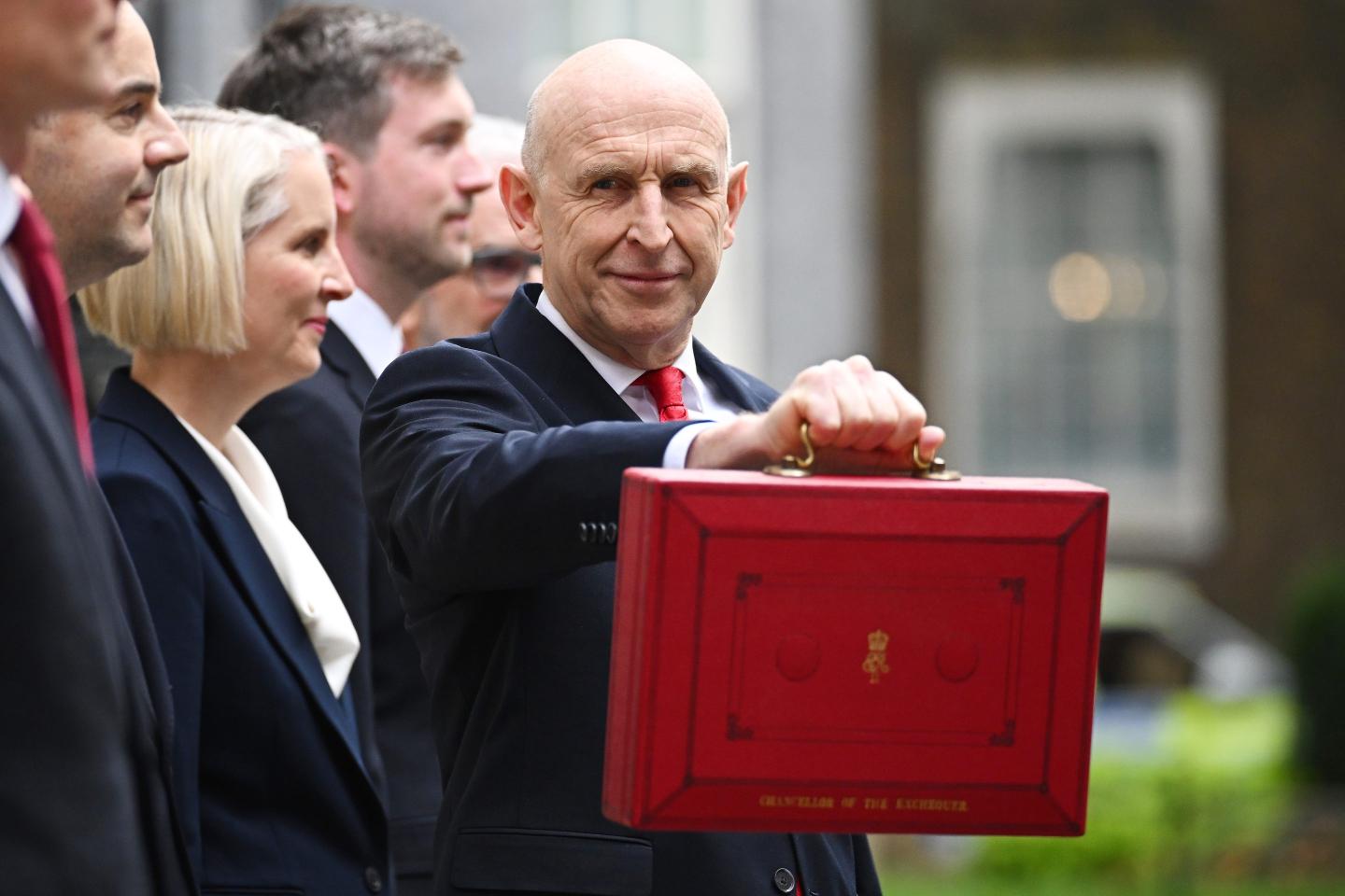 Treasury chief John Healey leaves to present the budget to Parliament.