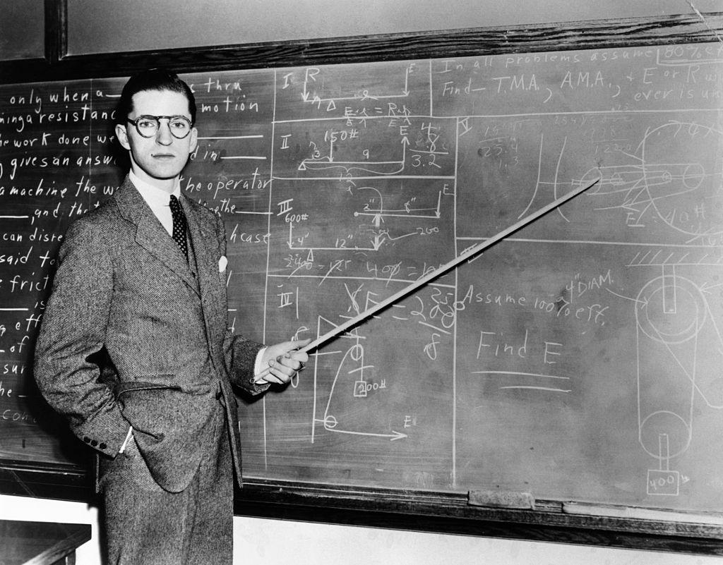 Old photo from approx. 1940s of man teaching at a chalkboard.
