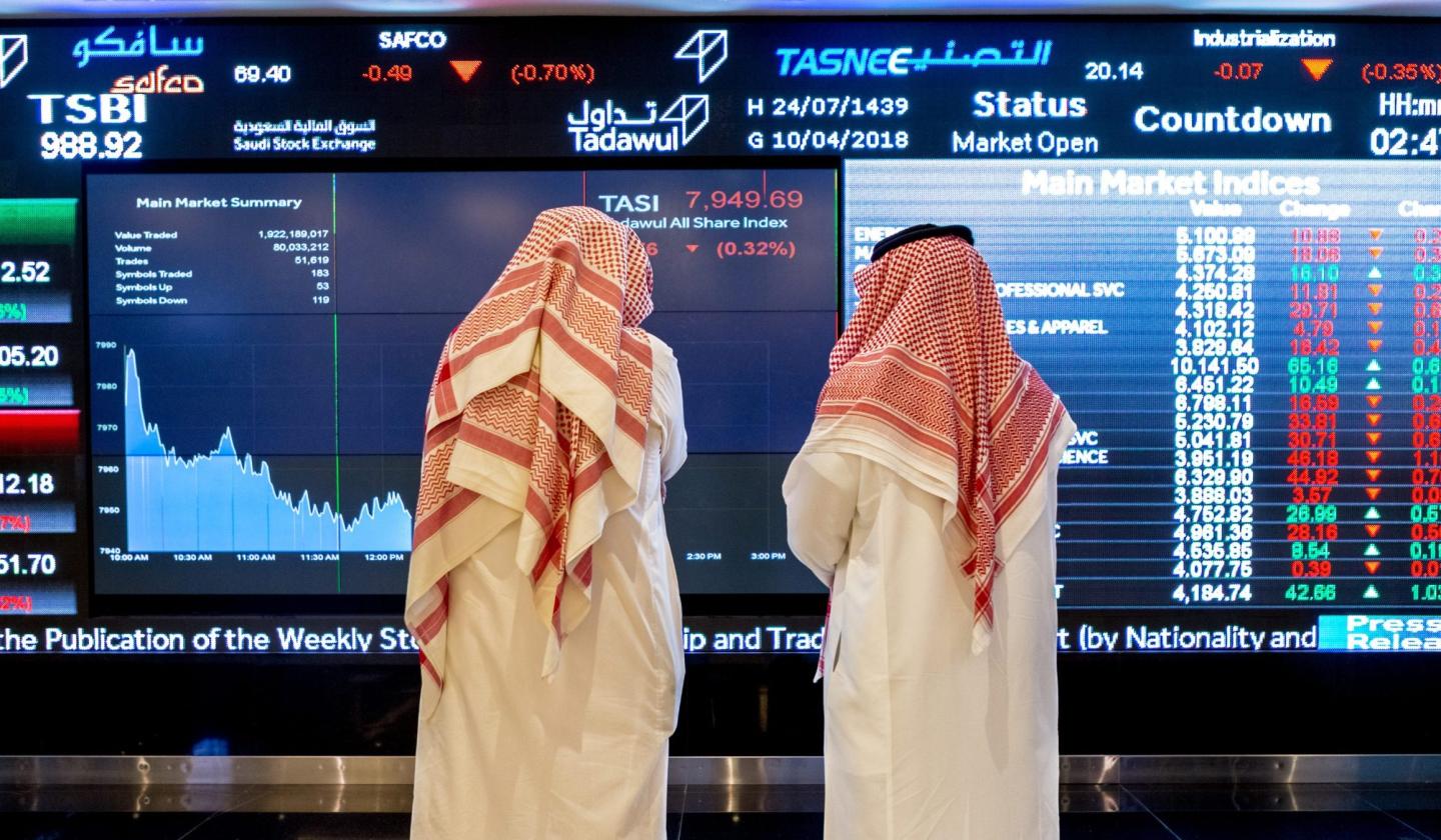 Visitors look at stock price information displayed on a digital screen inside the Saudi Stock Exchange, also known as the Tadawul, in Riyadh, Saudi Arabia, on Tuesday, April 10, 2018.